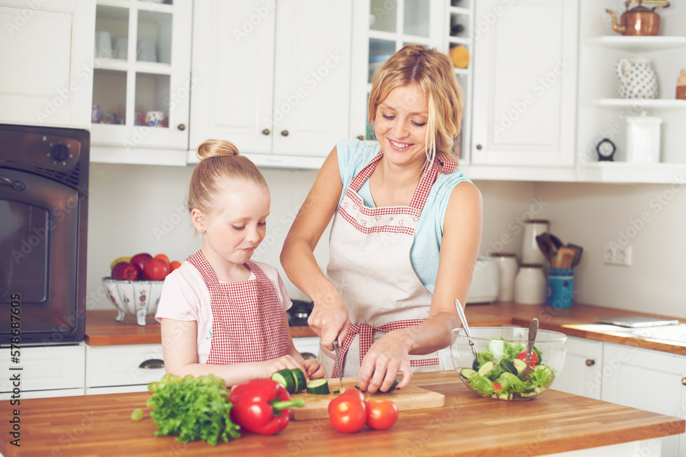 Making a delicious lunch together. Young mother and her daughter making a salad together. Making a delicious lunch together. Young mother and her daughter making a salad together.