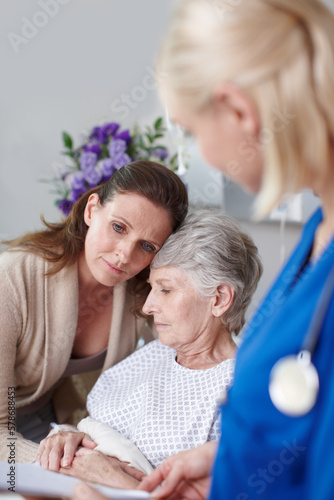 Donw worry, theres still hope. A daughter consoling her mother in the clinic as a young nurse looks on. photo