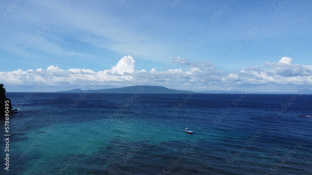 Aerial view of the sea surface and clouds. Small boat in the lagoon.