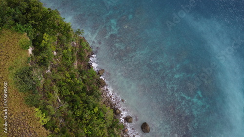 Aerial view of the coastline of an island covered in jungle.