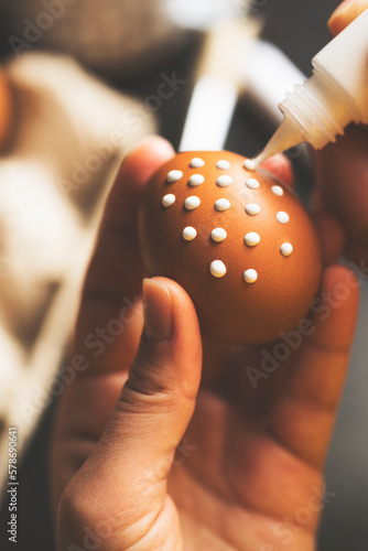 DIY handpainted easter eggs. Hand pianting white dots on brown egg. photo