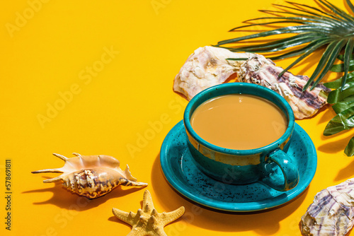 A cup of coffee in a marine style. Starfish, shells, palm leaves. Hard light, dark shadow