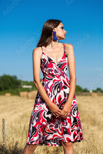 Portrait of a young woman with bright makeup posing on a mown wheat field