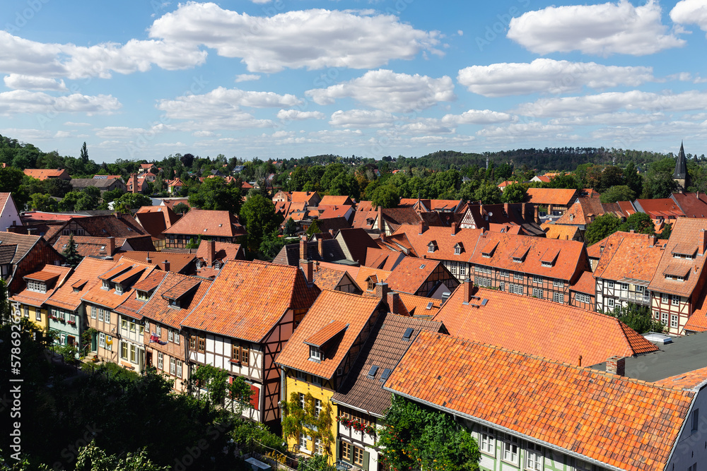 Scenic panoramic view traditional shingle tiled red rooftop old ancient medieval european german small town Quedlinburg church against blue sky background. Unesco heritage list travel destination