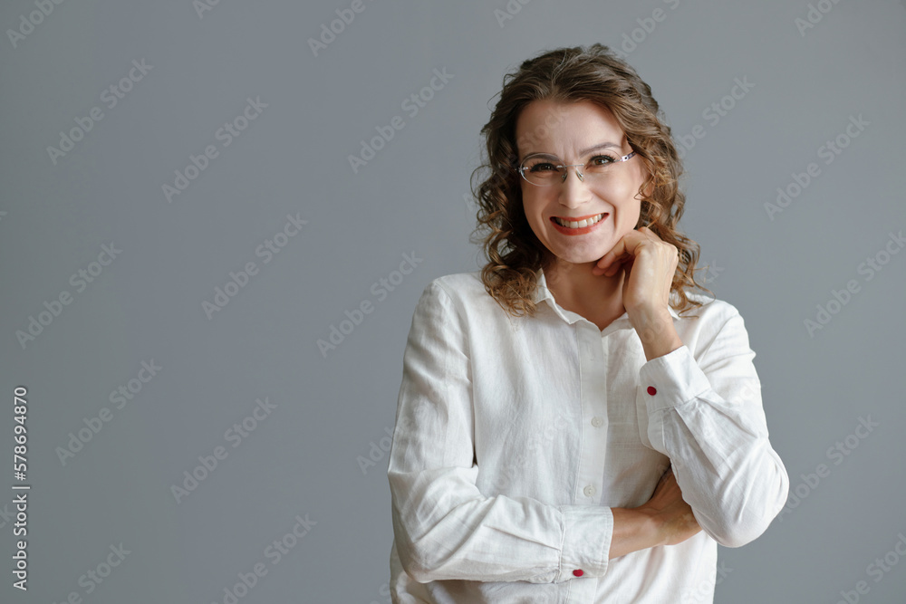 Studio portrait of smiling mature woman in glasses posing against grey wall Studio portrait of smiling mature woman in glasses posing against grey wall