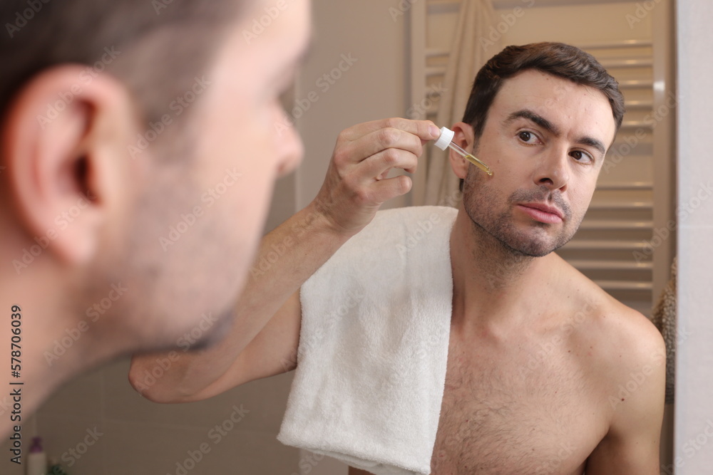 Man applying serum drops in the bathroom Man applying serum drops in the bathroom