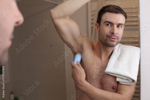 Man applying deodorant in the bathroom 