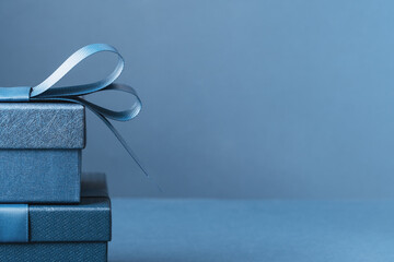 Two Luxury gift boxes with a blue bow on dark blue. Side view monochrome . Fathers day or Valentines day gift for him. Corporate gift concept or birthday party. Festive sale copy space banner