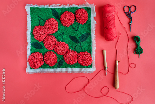 Top view of  red embroidered flowers on green, punch needles, ya photo