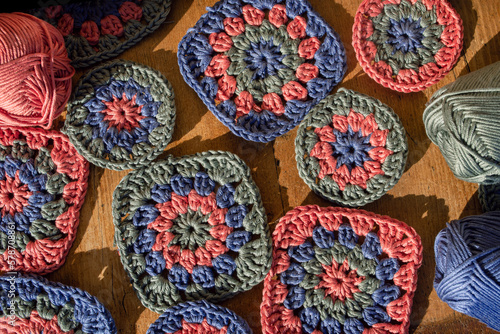 Top view of granny squares with skeins of cotton on wooden surfa