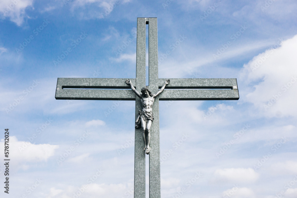 Big metal christian cross high in the blue sky. Symbol of love for Jesus. Catholic church monumental construction. Crucified jesus christ. Outdoor pray.