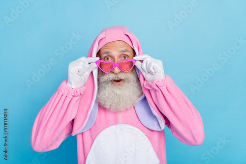Photo of positive man dressed pink rabbit costume sunglass hands touching glasses unbelievable sale isolated on blue color background