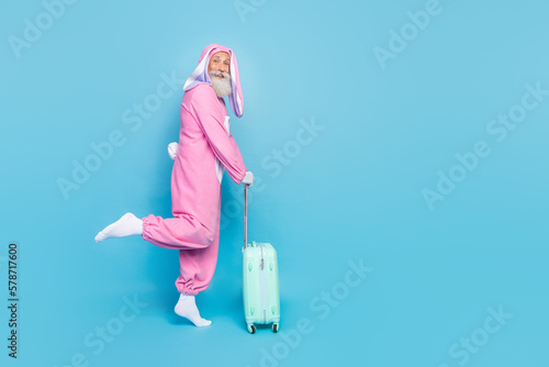 Full length photo of positive granddad hold suitcase empty space isolated on blue color background photo
