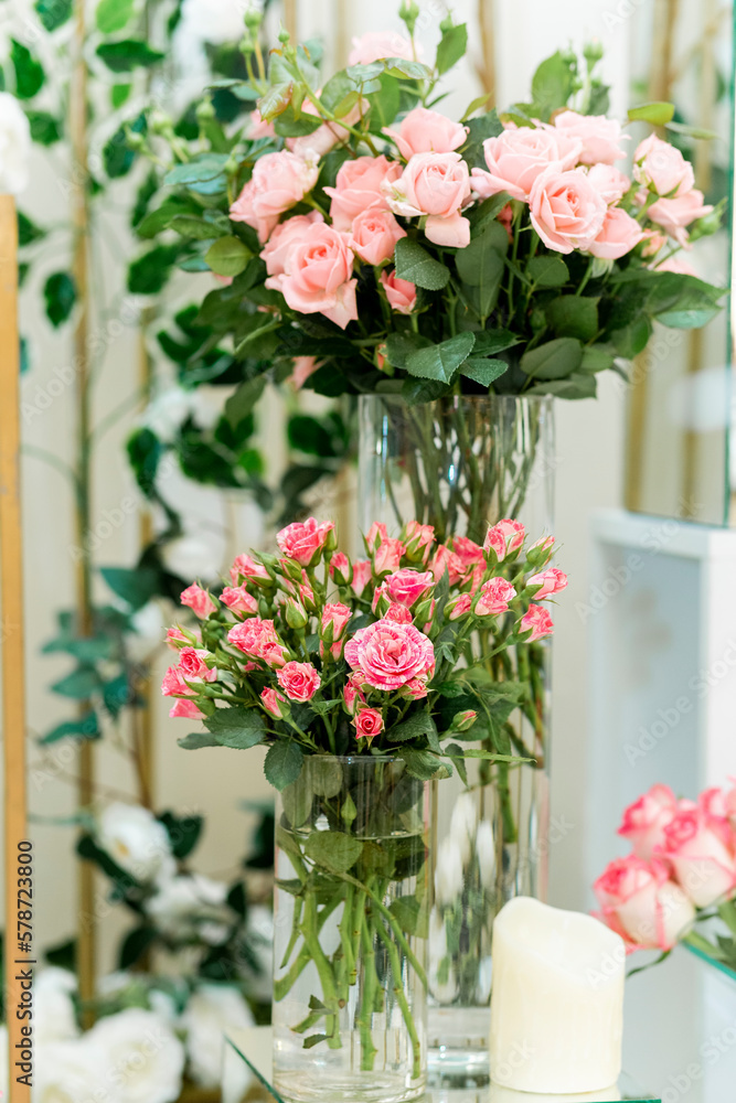 Closeup vertical shot of natural roses with vibrant colours arranged in glasses on a wedding day