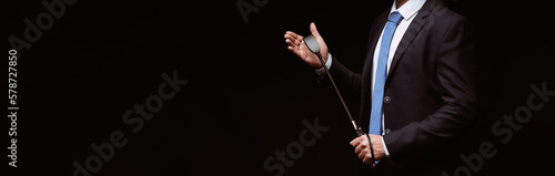 Male dominant businessman in a suit holding a leather whip Flogger for domination in BDSM sex. Panoramic wide horizontal photo for banner head cover