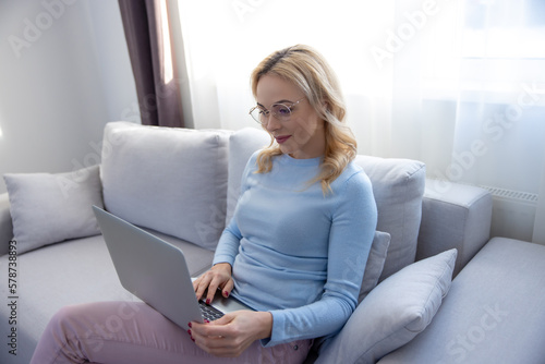 Tranquil concentrated lady in eyeglasses typing on her laptop