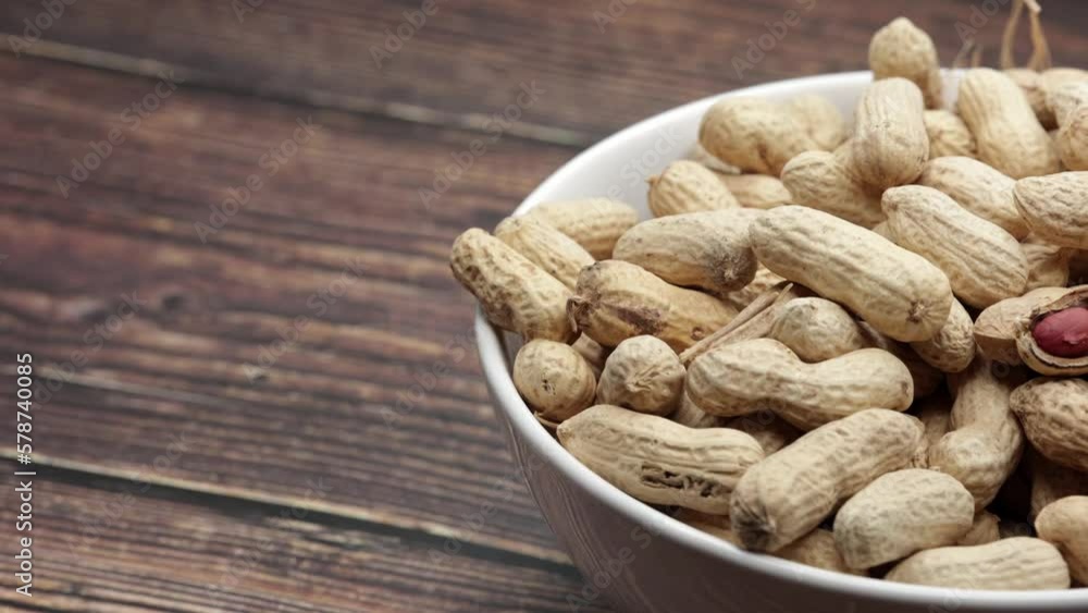 Raw Peanuts And Open Nut In White Bowl Cup On Wooden Board. Dolly Slider Shot. 4k, 60 FPS. Raw Peanuts And Open Nut In White Bowl Cup On Wooden Board. Dolly Slider Shot. 4k, 60 FPS.