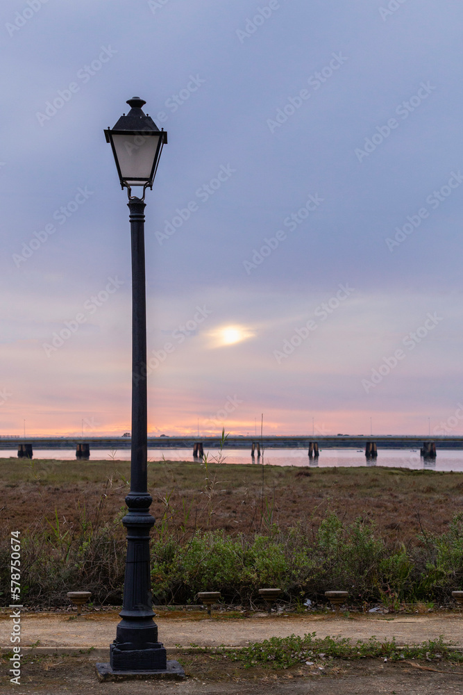 A lamp post with the sun setting behind it
