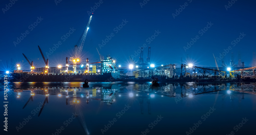 shipyard dry dock maintenance and repair container ship transport and oil ship tanker, crane work and commercial port reflection in water, at night over lighting in sea long exposure blue color tone, - obrazy, fototapety, plakaty 