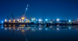 shipyard dry dock maintenance and repair container ship transport and oil ship tanker, crane work and commercial port reflection in water, at night over lighting in sea long exposure blue color tone,