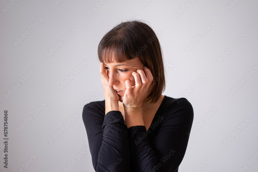 Portrait of a girl on white background. Brown short hair girl. Girl covering her face with her clasped hands, we only see her eyes. Portrait of a girl on white background. Brown short hair girl. Girl covering her face with her clasped hands, we only see her eyes.