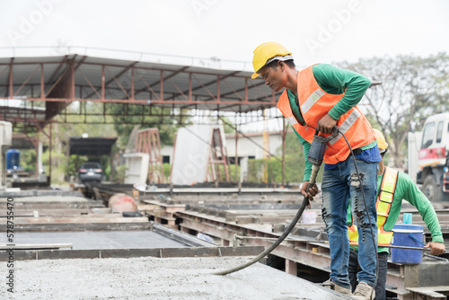 Construction technician uses concrete vibration generator during leveling concrete. Construction worker using concrete vibrator removal air bubbles for maximum strength in concrete photo