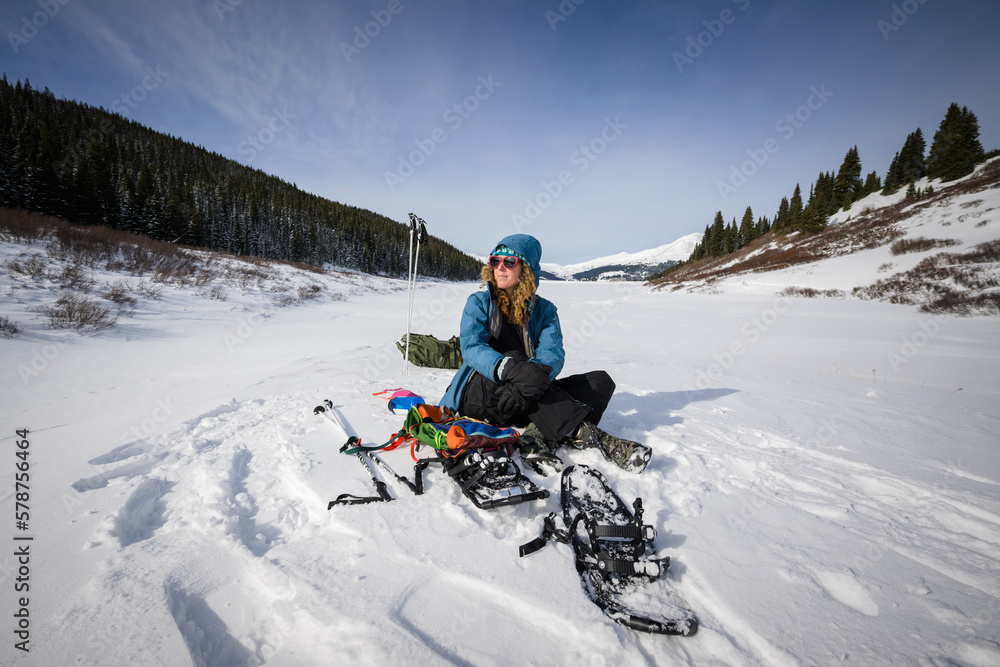 a young woman hiking in the mountains on snowshoes