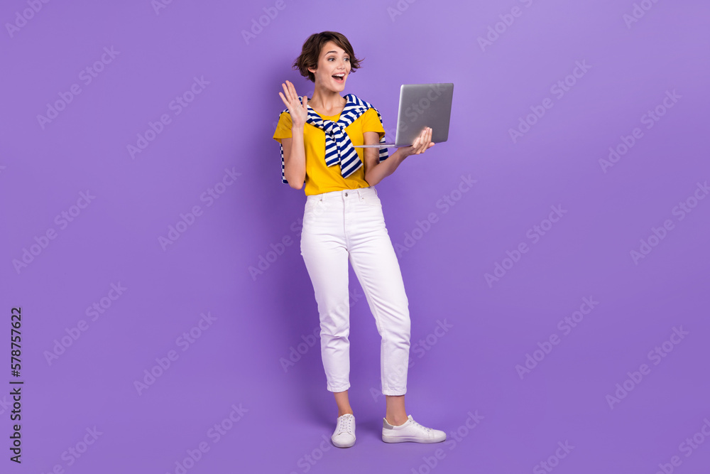 Full length photo of positive lady stylish clothes chatting friends followers arm greetings empty space isolated on purple color background Full length photo of positive lady stylish clothes chatting friends followers arm greetings empty space isolated on purple color background