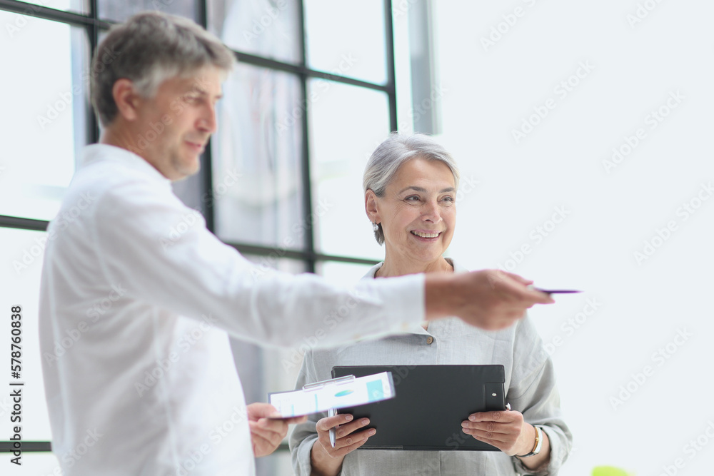 Fototapeta premium businessman showing something to mature businesswoman seen throu