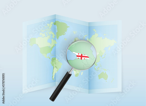 A folded world map with a magnifying lens pointing towards Georgia. Map and flag of Italy in loupe.
