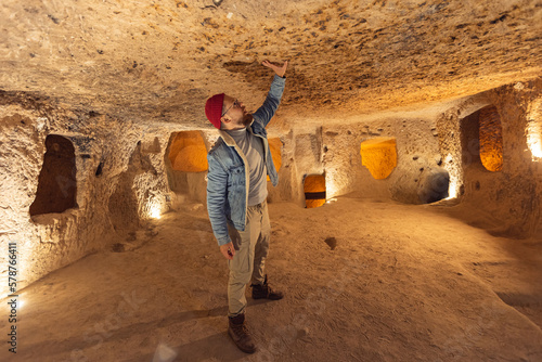 Tourist man in Kaymakli underground city ancient cave in Cappadocia, Turkey photo