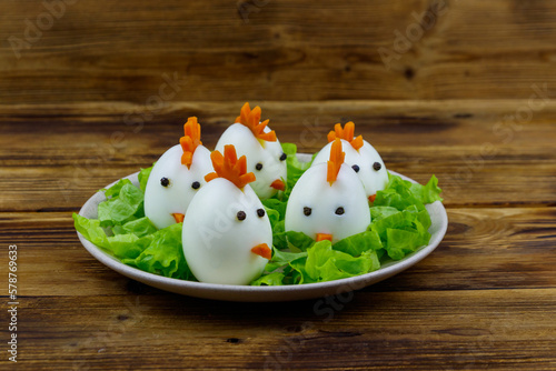Funny easter breakfast with boiled eggs as chicks on wooden table © olyasolodenko