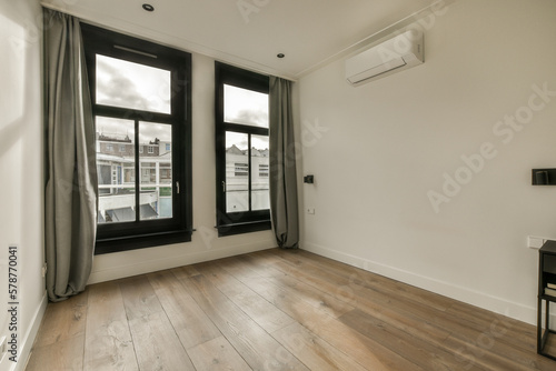 an empty room with wood flooring and two large windows looking out onto the cityscapea photo taken from inside photo