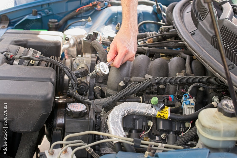 Automobile mechanic reaching into engine bay with socket wrench Automobile mechanic reaching into engine bay with socket wrench