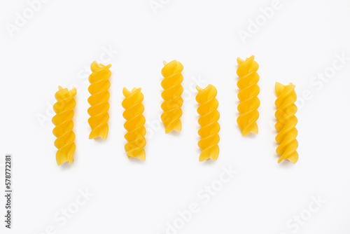 Dry pasta in the form of spirals on a white isolated background. Twisted pasta laid out in a row. Italian cuisine in the form of durum wheat pasta. Delicious national dish