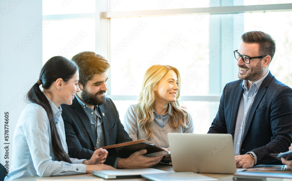 Group of entrepreneurs having a business meeting at office. Confidence business people laughing and communicating with each other around conference table. Group of entrepreneurs having a business meeting at office. Confidence business people laughing and communicating with each other around conference table.