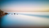  a long exposure photo of a body of water with rocks in the foreground.  generative ai