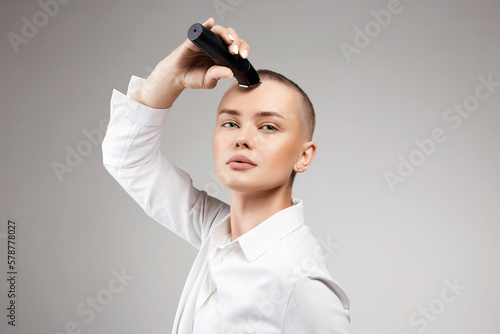 beautiful young woman cutting her hair. bald Girl with hairclipper