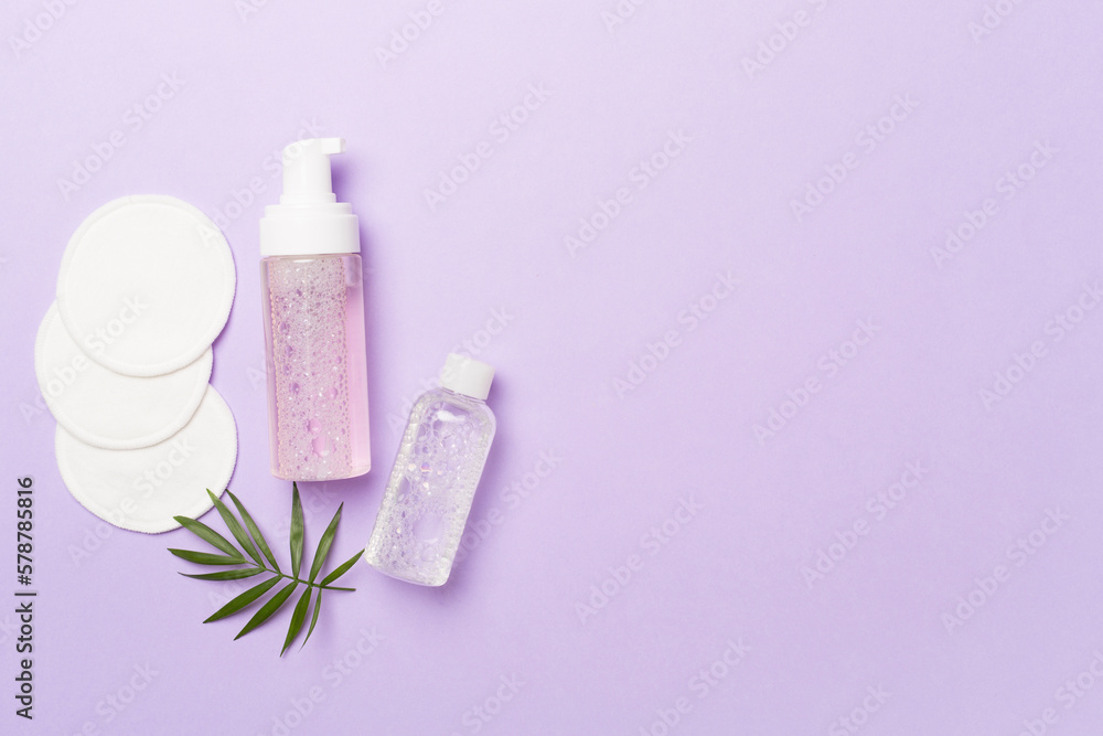 Foaming facial cleanser and micellar water with eco pads on color background, top view Foaming facial cleanser and micellar water with eco pads on color background, top view