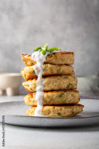 Greek zucchini fritters Kolokithokeftedes on gray background. Zucchini pancakes with feta and herbs, served with greek yogurt. photo