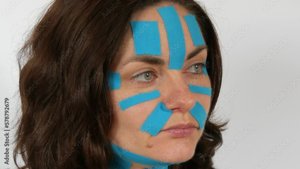 Young woman applied light blue kinesio strips taping face, forehead