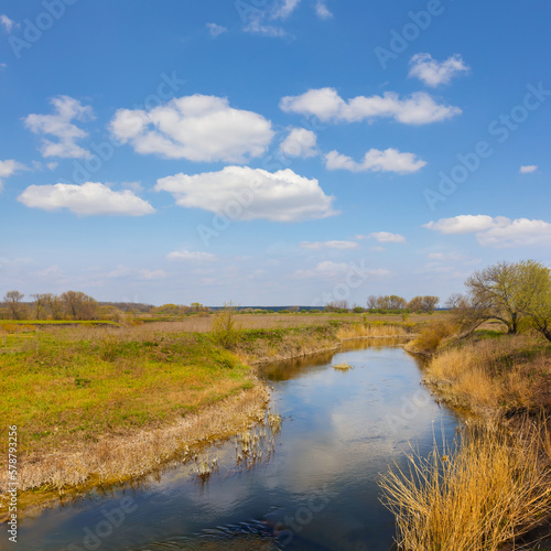 calm river flow among prairie under blue cloudy sky