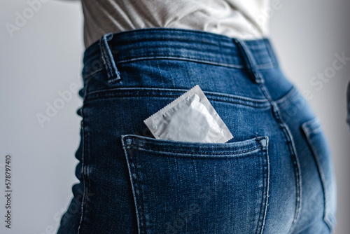 Detalle de un preservativo en el bolsillo trasero de los jeans de una mujer. Concepto de sexo seguro. Protección contra embarazos y enfermedades de transmisión sexual. Métodos anticonceptivos.