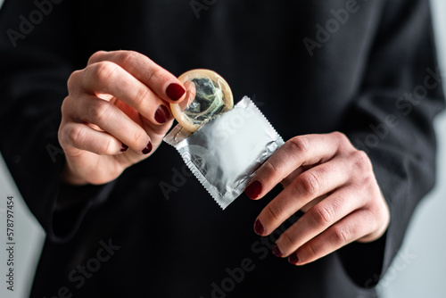 Detalle de una mujer abriendo el envoltorio de un preservativo masculino. Concepto de sexo seguro. Protección contra embarazos y enfermedades de transmisión sexual. Métodos anticonceptivos