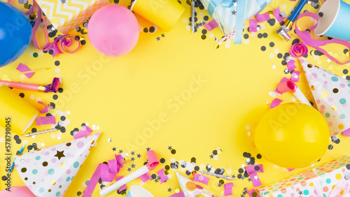 Birthday party attributes. Colorful balls, confetti, gifts, candles for cake. Yellow background. Top view. Copy space