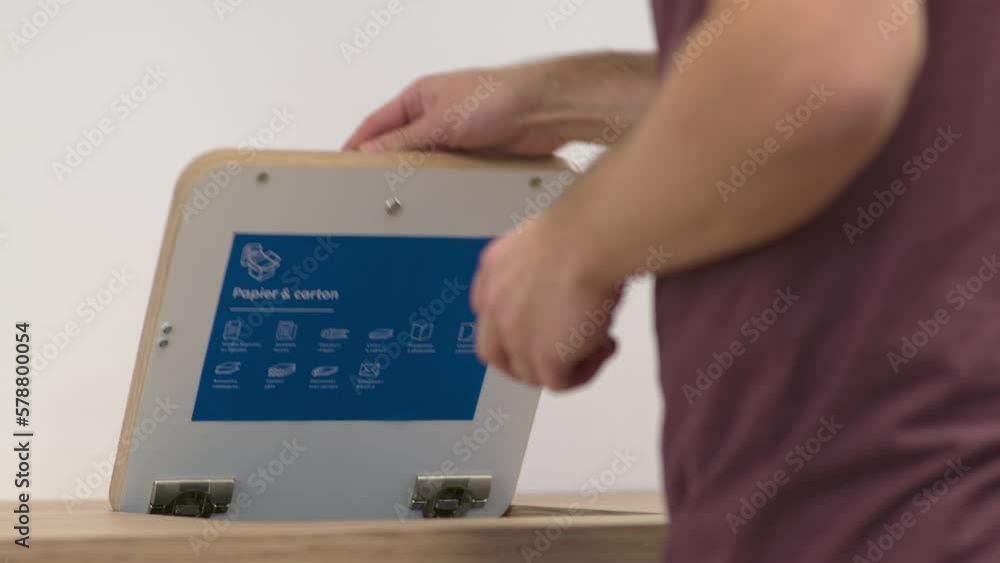 Un employé dans une entreprise jette du papier dans une poubelle de tri pour le recycler