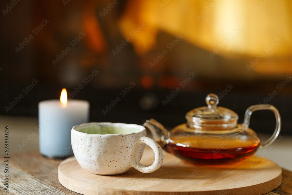 Glas teapot on the table in room with fireplace cozy autumn still life. Glas teapot on the table in room with fireplace cozy autumn still life.