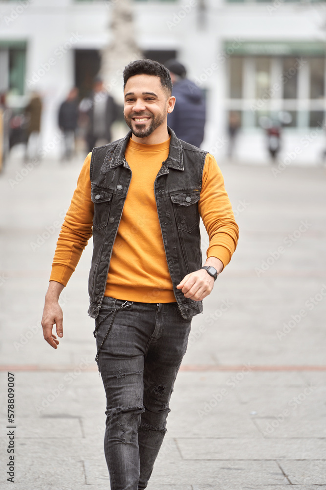 Man smiling while walking outdoors on the street. Urban concept.