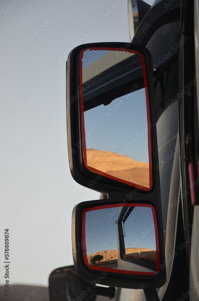 The dry desert of Jordan reflected in a trunk side view mirror
