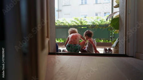 Картината върху платно Children sitting by door step putting shoes on outside